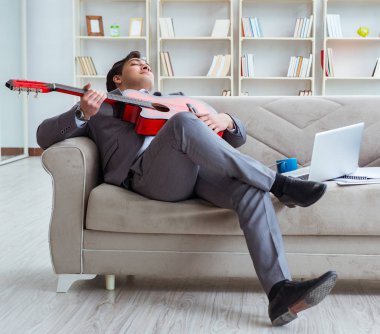 Evde gitar çalan bir iş adamı.