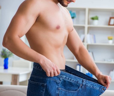 Kilo verme konseptinde büyük beden pantolon giyen bir adam.