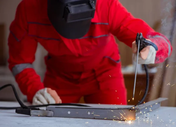 Reparador joven con un electrodo de pistola de soldadura y una soldadura de casco —  Fotos de Stock