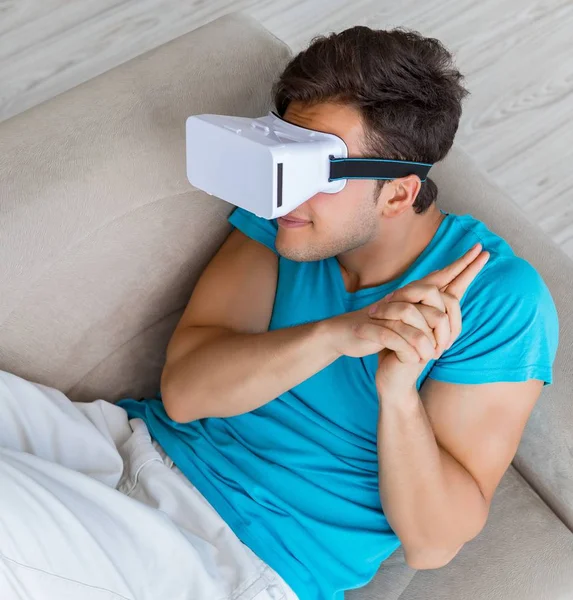 Молодий чоловік в окулярах VR, що розслабляються на дивані — стокове фото