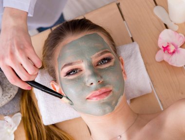 Yüz maskeli, spa sağlık konsepti olan genç bir kadın.