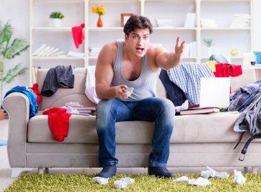 Genç adam dağınık bir odada çalışıyor.