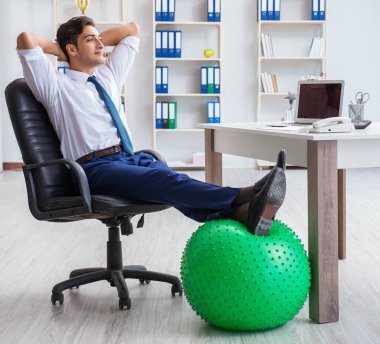 Genç işadamı iş yerinde spor yapıyor.