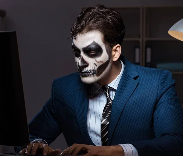 De zakenman met het enge gezichtsmasker die laat op kantoor werkt. — Stockfoto