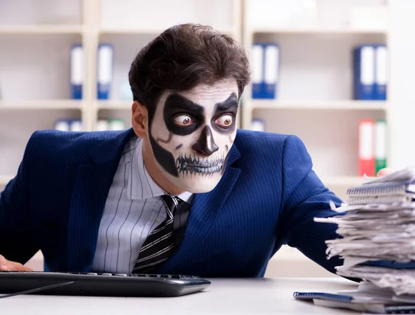 Businessmsn with scary face mask working in office