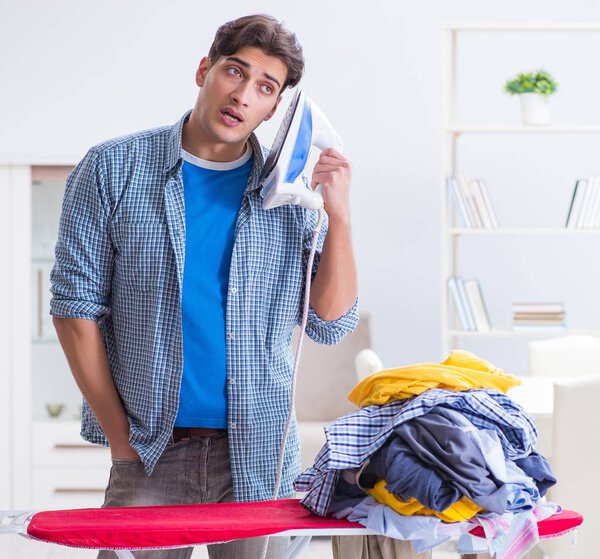 Молодой человек муж гладит одежду дома