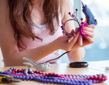 Kadın evde mücevher yapıyor.