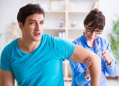 Doktor çekiçle sinir reflekslerini kontrol ediyor