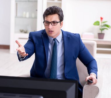 İş adamı ofiste televizyon izliyor.