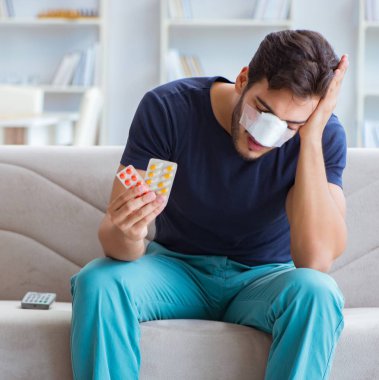 Genç adam estetik cerrahi burnundan sonra evde iyileşiyor.