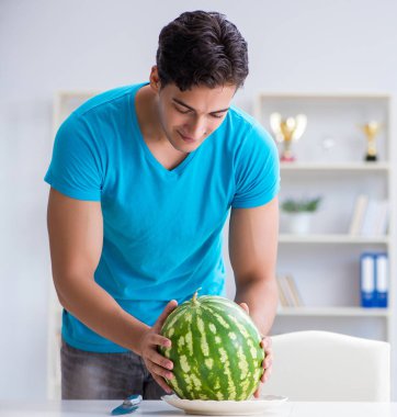 Evde karpuz yiyen bir adam.