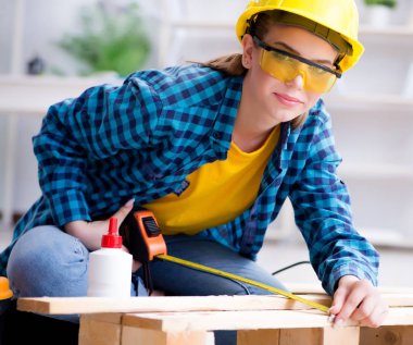 Tamirci kadın marangoz ahşap döşemeleri kesiyor.