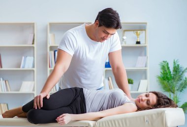 Genç doktor kayropraktik uzmanı kadın hastaya masaj yapıyor.