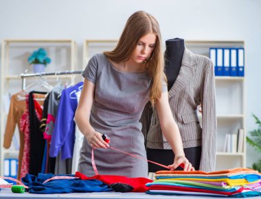 Atölyede çalışan genç bayan terzi yeni elbise üzerinde çalışıyor.