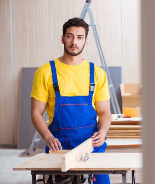 Genç tamirci marangoz odun kesiyor.