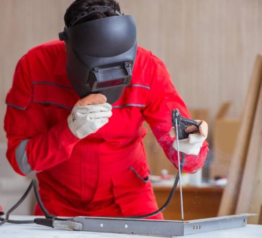Kaynak tabancası elektrot ve kask takan genç bir tamirci.