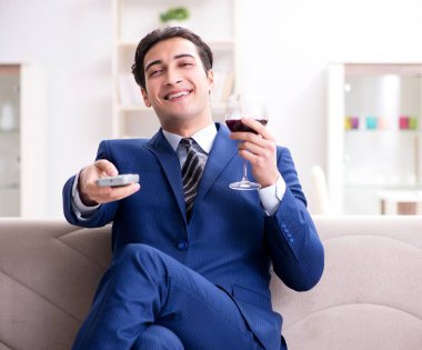 İş adamı evde oturmuş şarap içiyor.