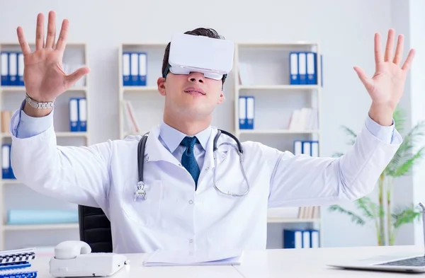 Νεαρός γιατρός με ακουστικά εικονικής πραγματικότητας που εργάζεται στο γραφείο — Φωτογραφία Αρχείου