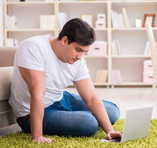 Man werkt op laptop thuis op tapijt vloer — Stockfoto