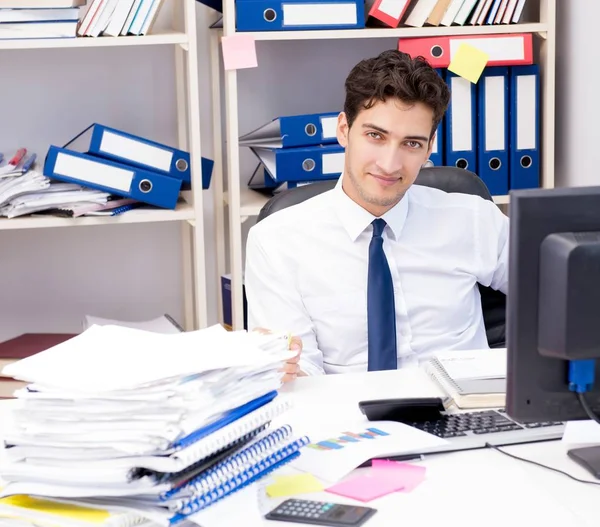 Geschäftsmann arbeitet im Büro mit Stapeln von Büchern und Papieren — Stockfoto