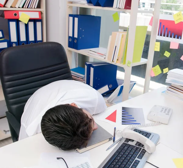 Uomo d'affari che lavora in ufficio con mucchi di libri e carte — Foto Stock