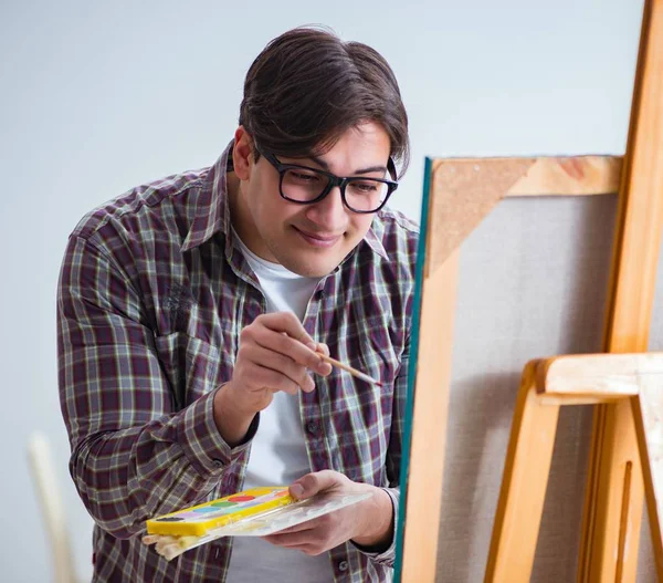 Молодий чоловік художник малює картини в яскравій студії — стокове фото