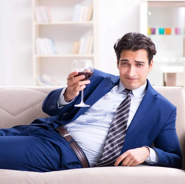 İş adamı evde oturmuş şarap içiyor.