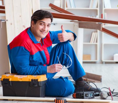 Genç marangoz ahşap kalaslarla çalışmaya ara veriyor.