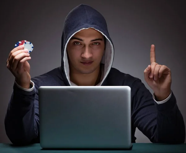 Young man wearing a hoodie sitting in front of a laptop computer — Stock Photo, Image