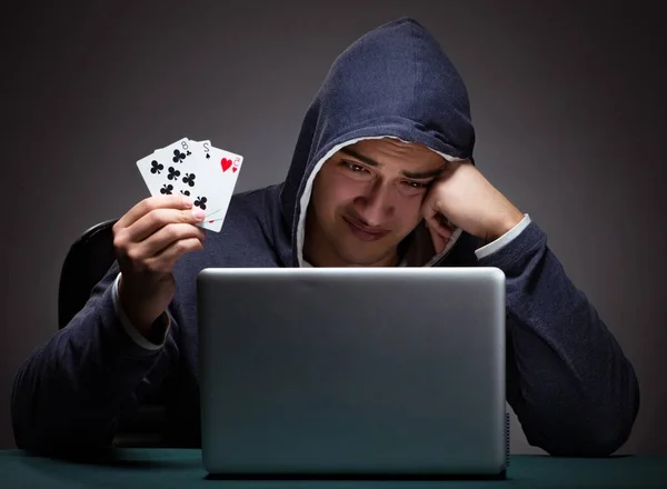 Jovem usando um capuz sentado na frente de um computador portátil — Fotografia de Stock