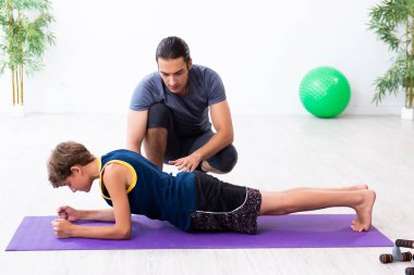 Genç baba ve oğlu egzersiz yapıyor.