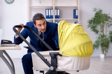 Genç baba ofiste yeni doğan bebeğe bakıyor.