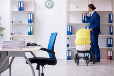 Genç baba ofiste yeni doğan bebeğe bakıyor.