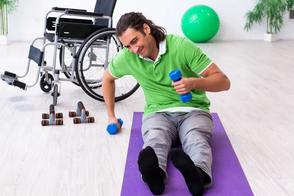 Young man in wheel-chair doing exercises indoors — Stock Photo, Image