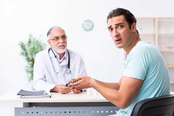 Ung man besöker gamla manliga läkare — Stockfoto