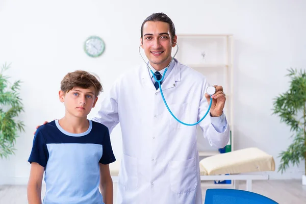 Giovane medico maschio esaminando ragazzo in clinica — Foto Stock