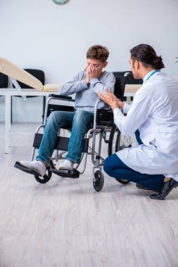 Genç erkek doktor pediatrist ve tekerlekli sandalyedeki çocuk.