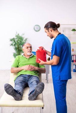 Yaşlı adam genç erkek gastroenteroloğu ziyaret ediyor.