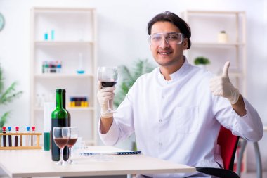 Erkek kimyager laboratuvarda şarap örneklerini inceliyor.