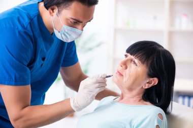 Yaşlı kadın estetik ameliyat için erkek doktoru ziyaret ediyor.