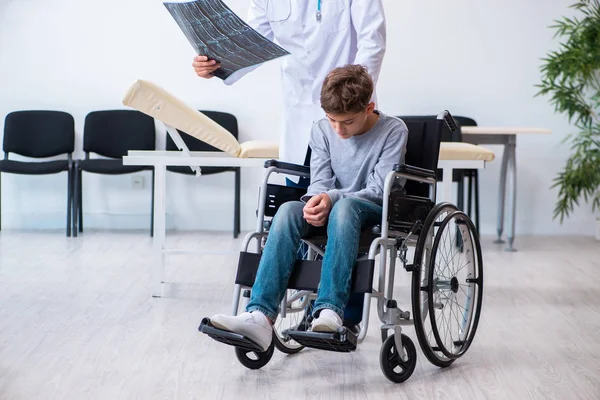 Joven doctor pediatra y niño en silla de ruedas —  Fotos de Stock