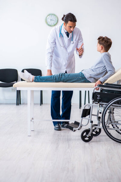 Young male doctor pediatrist and boy in wheel-chair