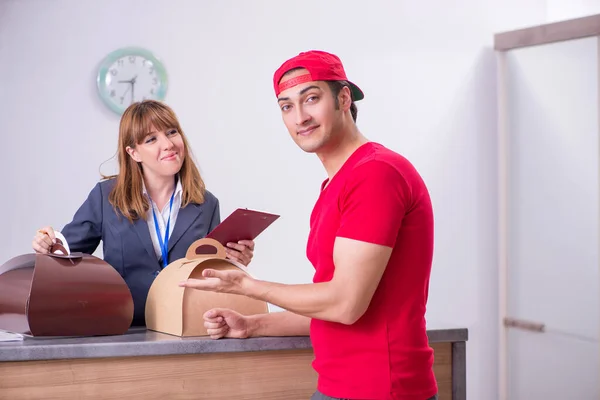 Jonge mannelijke koerier levert taart aan hotelreceptie — Stockfoto