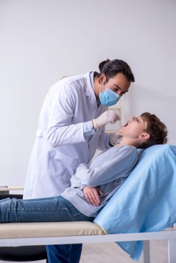 Genç çocuk hastanede doktoru ziyaret ediyor.