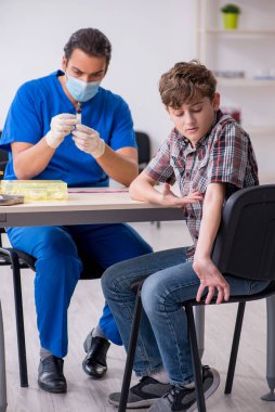 Genç çocuk hastanede doktoru ziyaret ediyor.