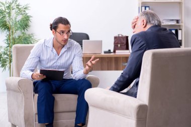 Yaşlı adam genç erkek doktor psikologunu ziyaret ediyor.