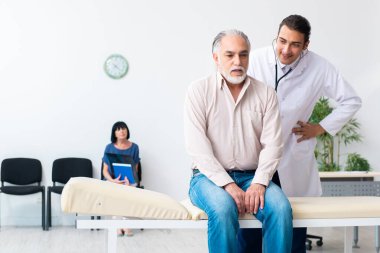 Yaşlı çift genç erkek doktoru ziyaret ediyor.
