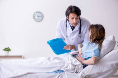 Erkek doktor koğuştaki kadın hastayı ziyaret ediyor.
