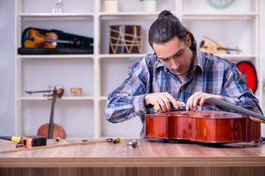 Genç yakışıklı tamirci çello tamir ediyor.