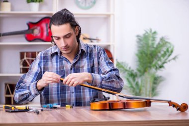 Kemanı tamir eden yakışıklı bir tamirci.